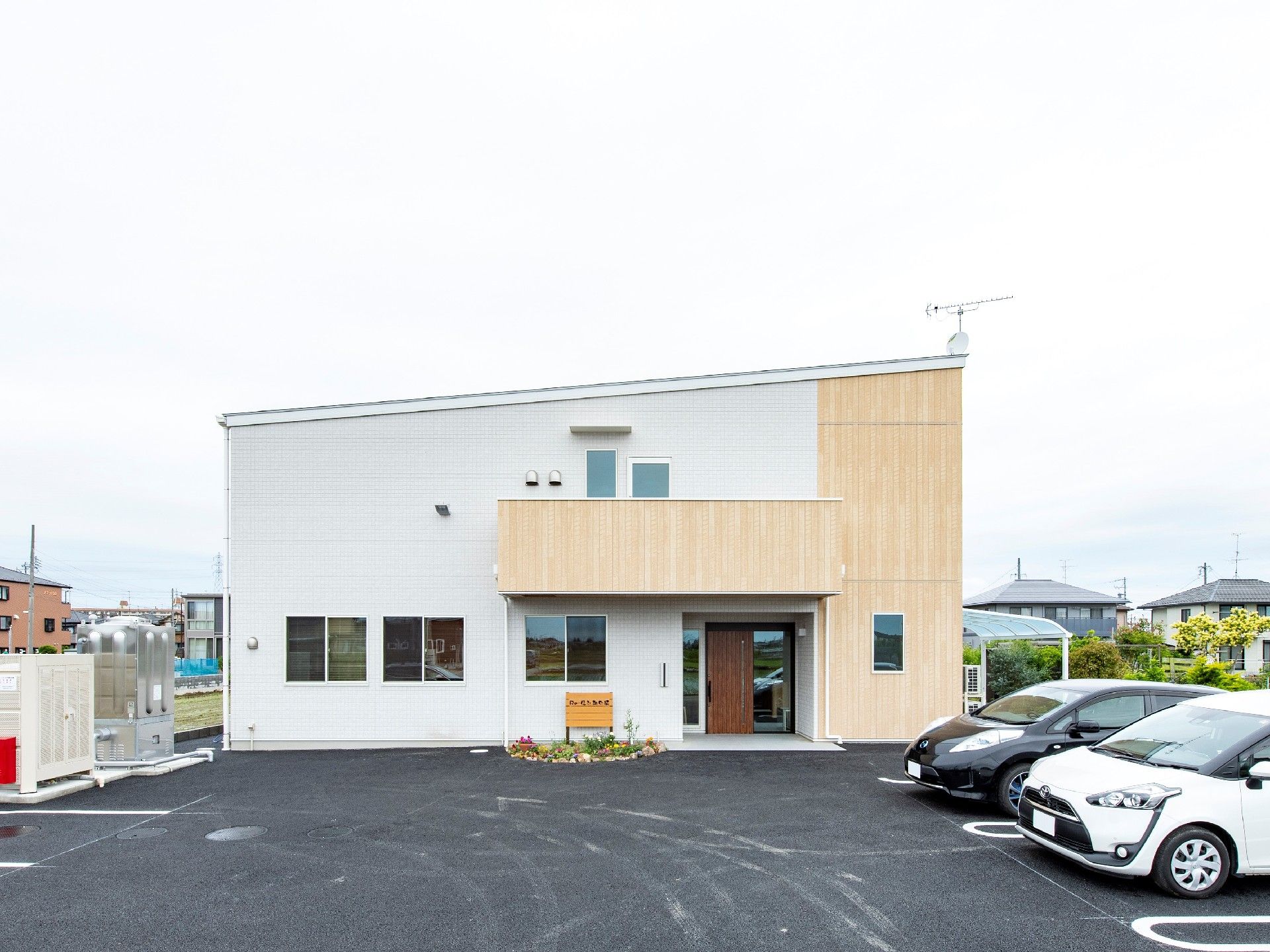 台形の形をした建てもの。入り口の屋根と右端はベージュ色に塗られている。