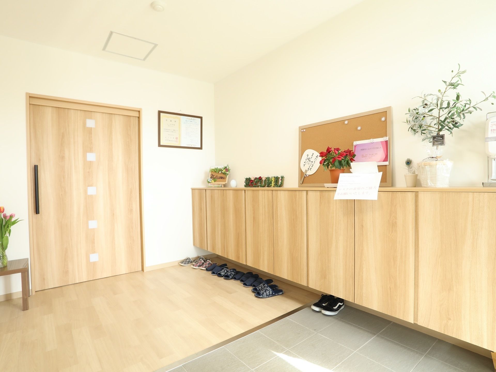 エントランスの壁には、扉の付いた木目調の靴箱が設置されている。床には段差がなく、車椅子でもスムーズに出入りできる造りである。
