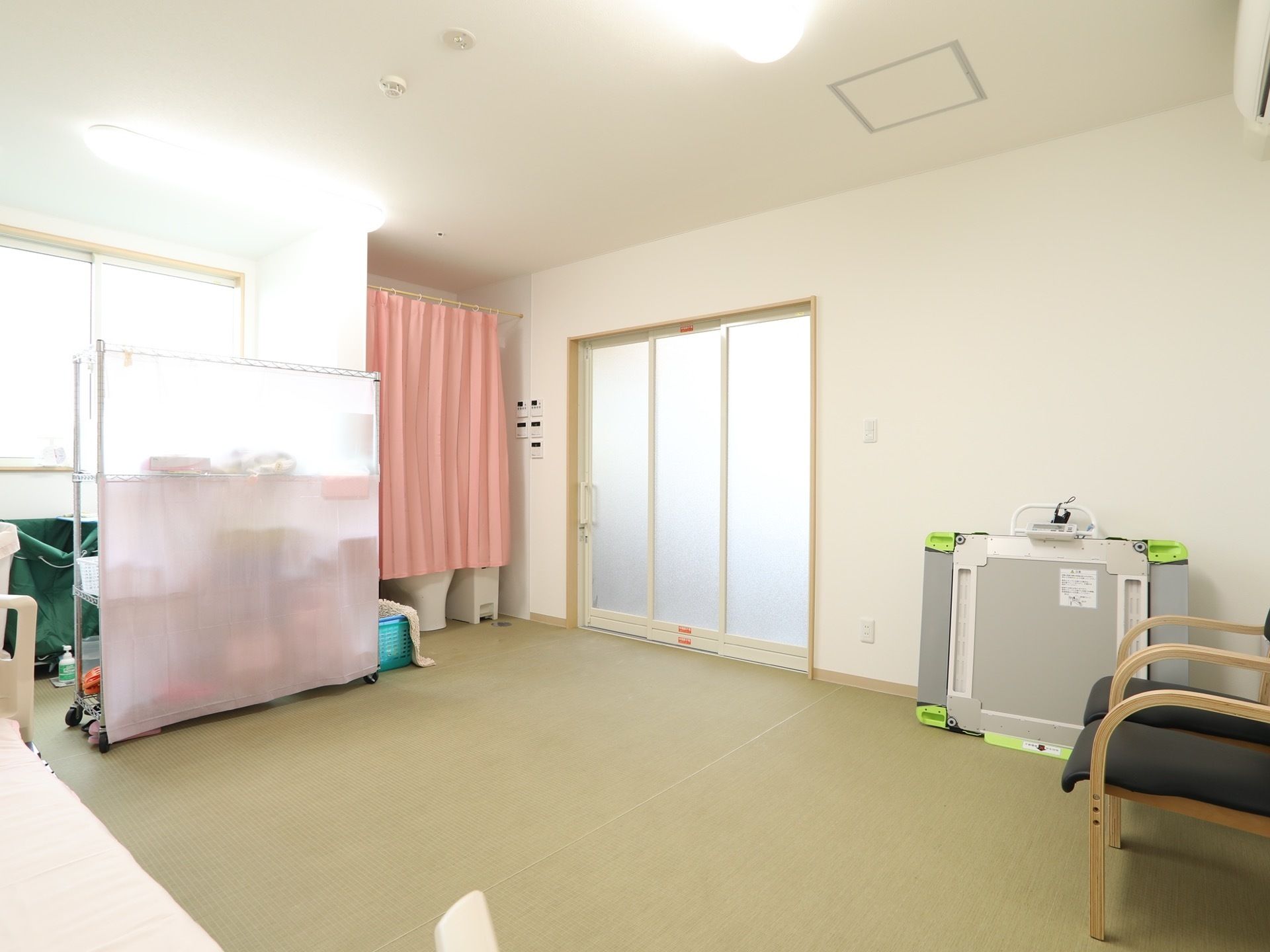 脱衣所は広々としており、車椅子でも楽に入れる。車椅子用の体重計が壁に立てかけられていて、側には椅子が2脚置かれている。
