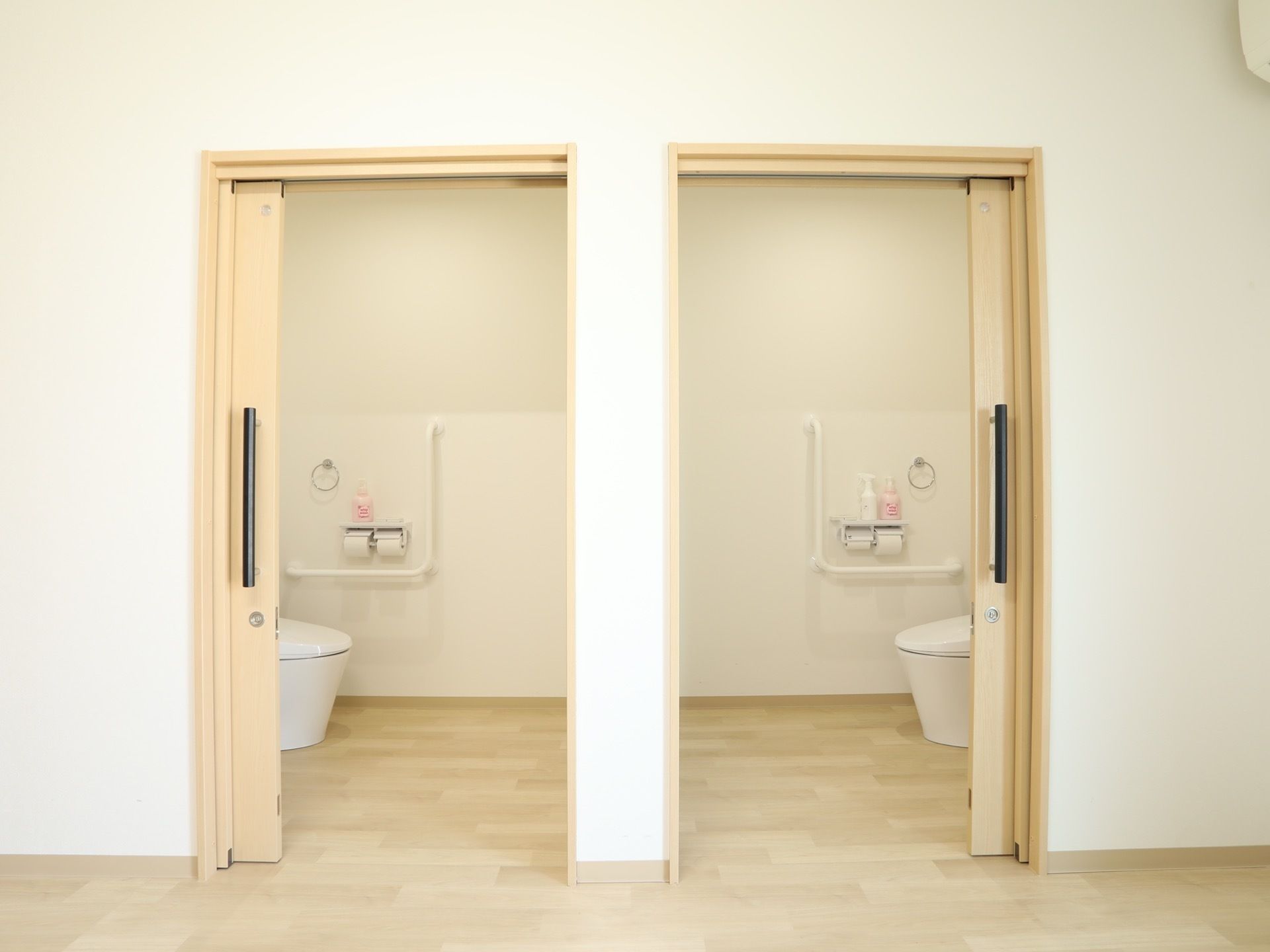 トイレのドアは引き戸式になっており、床には段差がない。中は車椅子でも入れる広さがあり、壁にはL字型の手すりが設置されている。