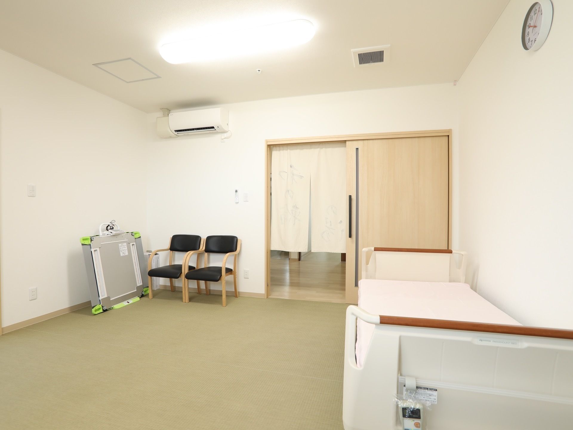 脱衣所の床は薄いグリーン色で、段差のない構造である。入口の引き戸が開いており、のれんが掛けられている。