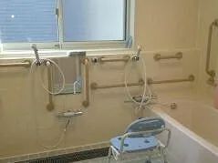 手すりがたくさんついている浴室には一人用の浴槽が設置され、大きな窓が付いている。