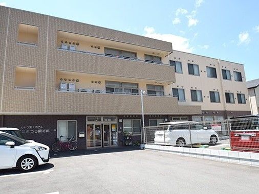 ３階建ての建物はブラウン系で落ち着いた雰囲気。各フロアにベランダが付き、駐車場もある。