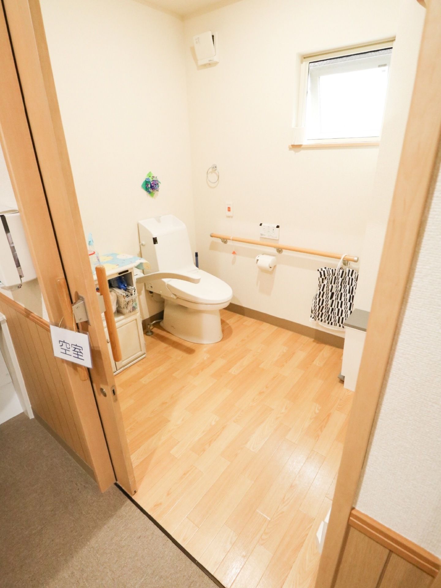 大きな取っ手がついた引き戸を開けた所に共用トイレがある。ふたつきの便座で、壁に横方向の手すりがかかっている。