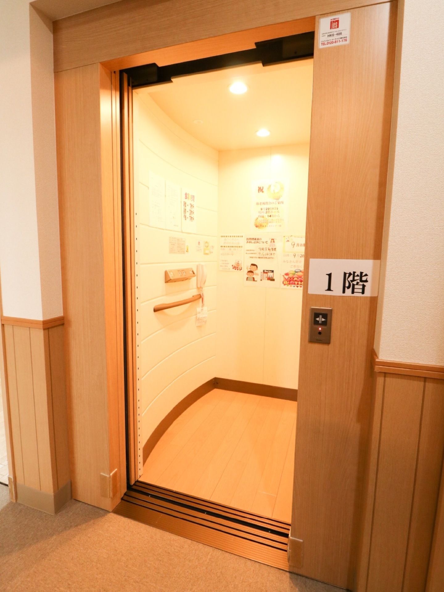 エレベーターがある。乗降口の右側の柱に、大きな文字で階数が表示されている。内部は電球色の照明で照らされている。
