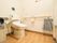 共用トイレは広いスペースに設置されている。横方向の長い手すりが壁に取り付けられていて、その端に袋がぶら下げられている。