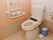 トイレは、洗浄暖房機能つきのふたなし便座である。水タンクの下に、汚物を入れる青色のバケツが置かれている。
