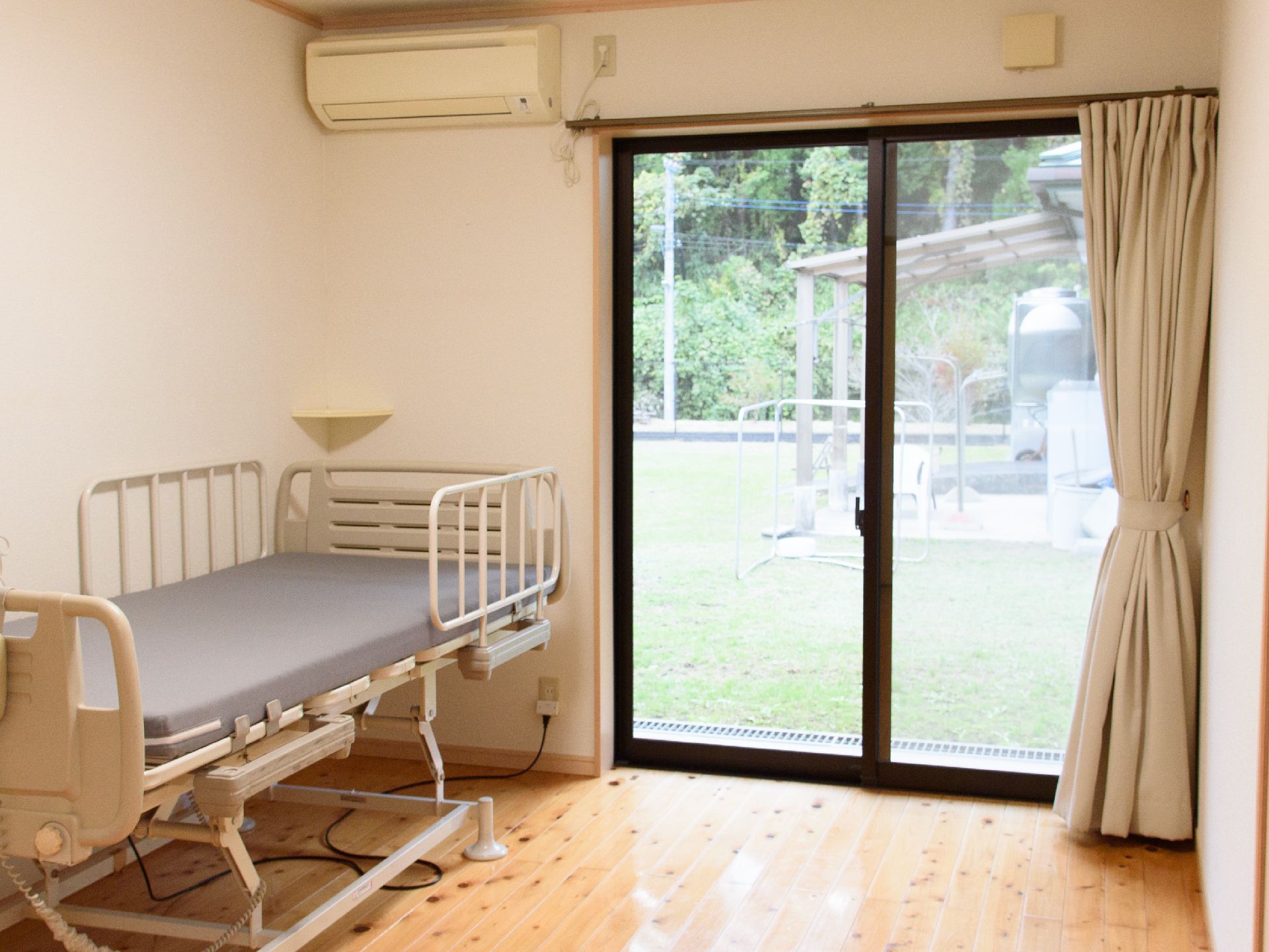 大きな窓からは芝生の庭が見える、介護用ベッド付きの居室