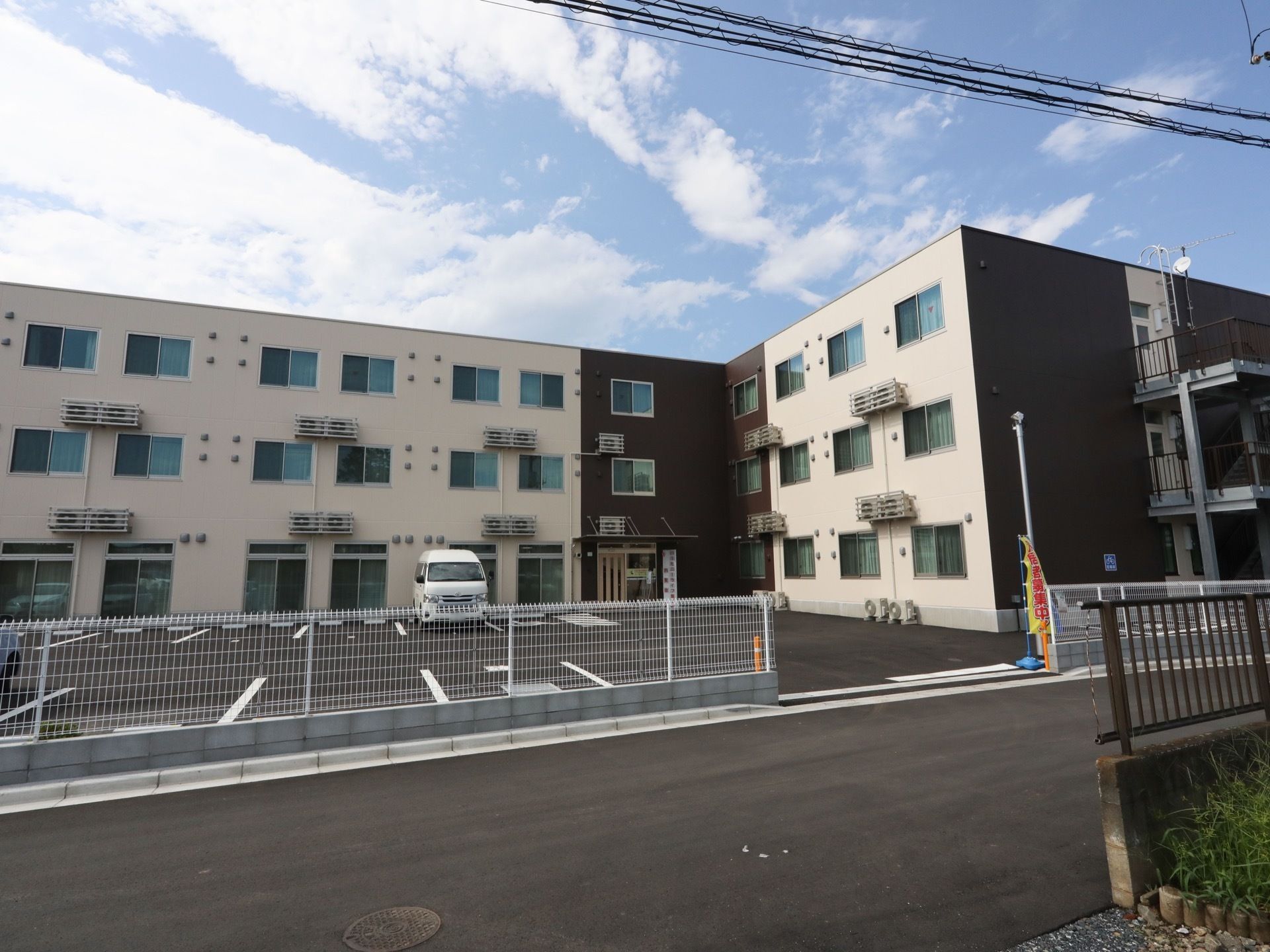 ベージュ色とブラウン色２色が使われた落ち着いた雰囲気の建物である。３階建てになっており、外階段がある。