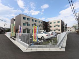 ベージュ色が基調の落ち着いた雰囲気の建物である。3階建てになっており、建物の前には広々とした駐車場が確保されている。