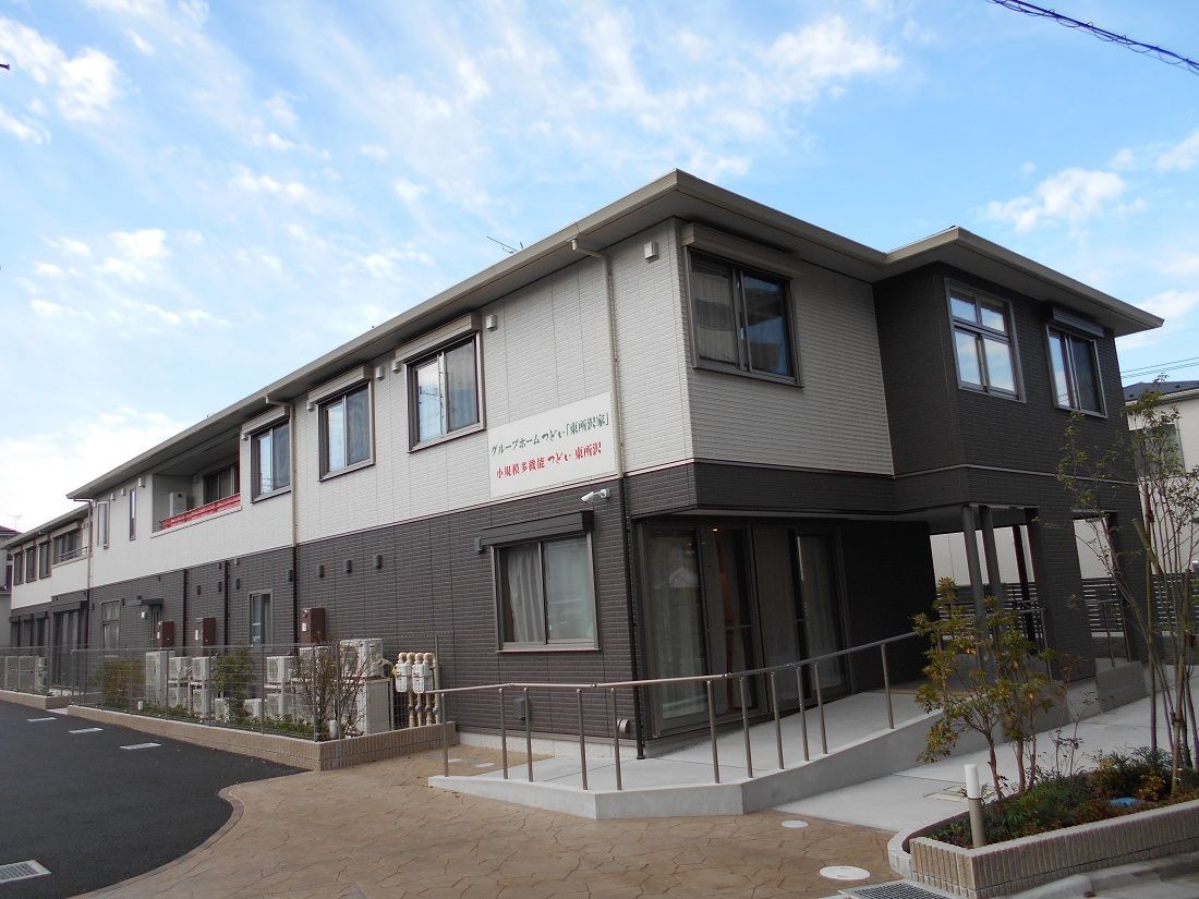 落ち着いた雰囲気の2階建ての建物。玄関にはスロープがあり、周辺には木も植えられている。