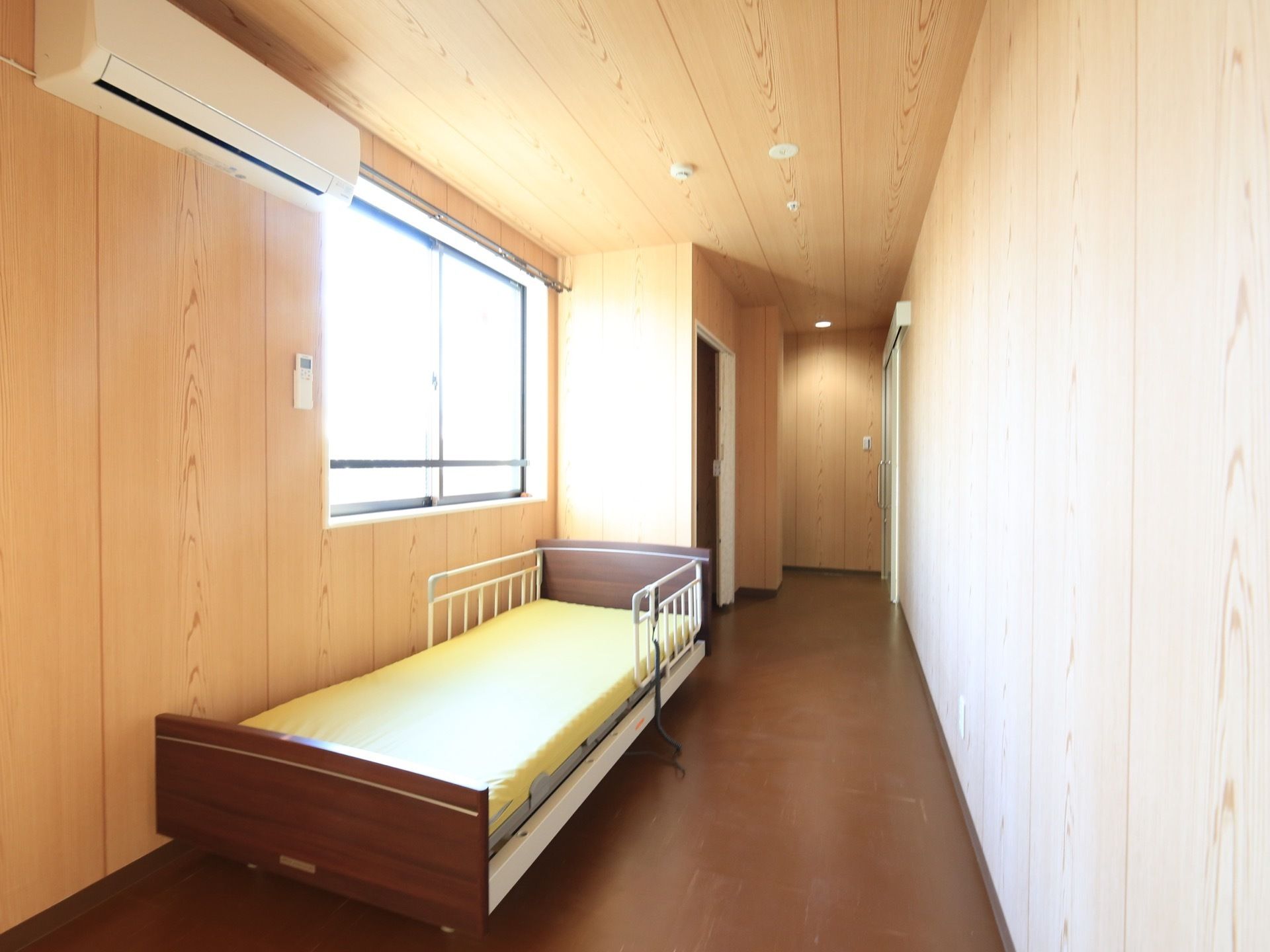 居室の壁や天井には木材が使われていて、あたたかみのあるデザインである。左側の壁には窓があり、明るい光が差し込んでいる。