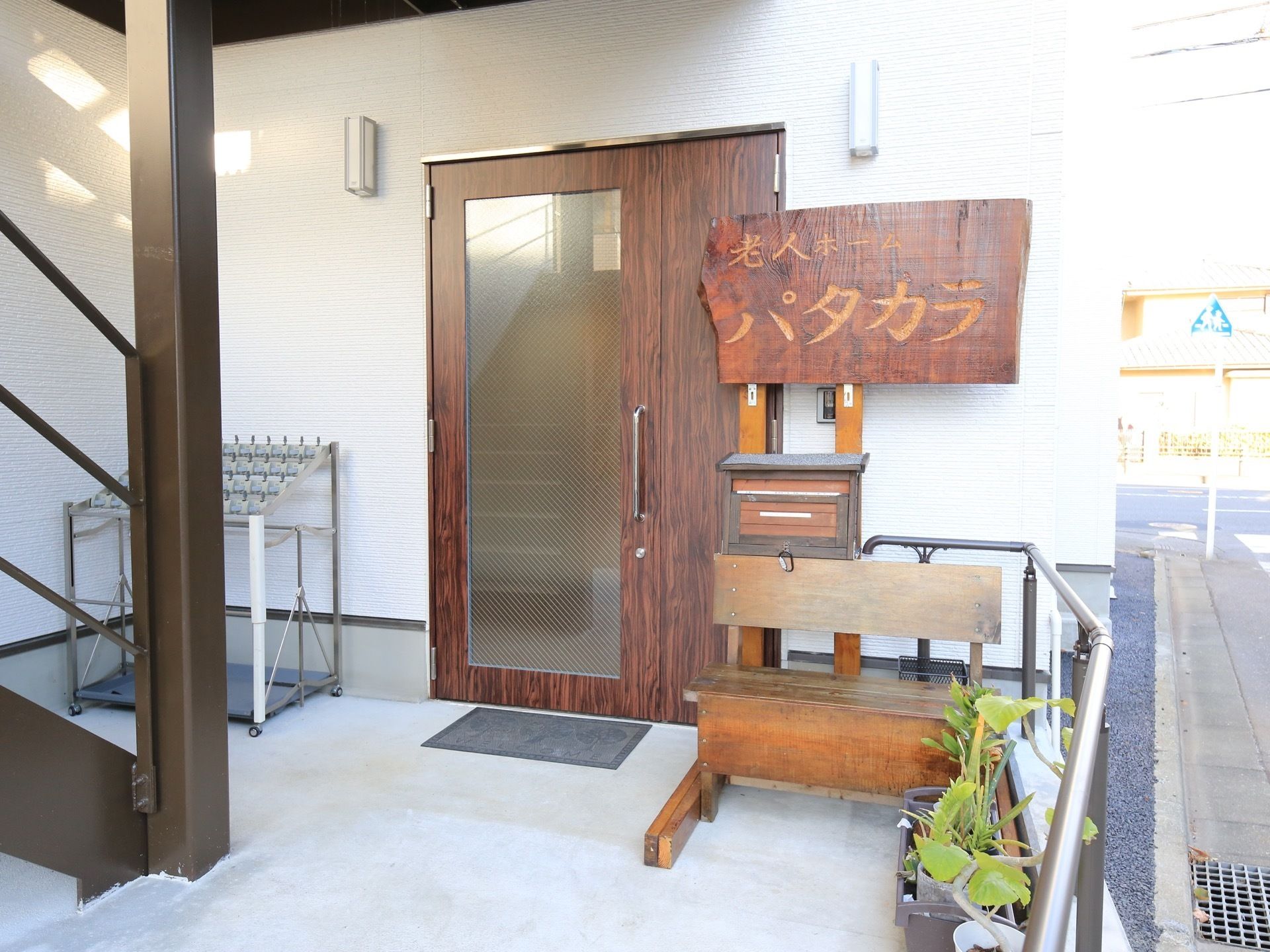 木目調のドアが設置されており、その右側に木製の看板が取り付けてある。看板には施設名称が手彫りで刻まれている。