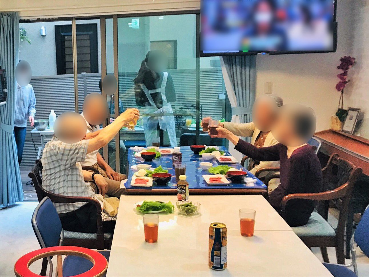 料理が並べられた食卓を囲む男女2名ずつのテーブル。コップを片手に持って乾杯をしようとしているところ。