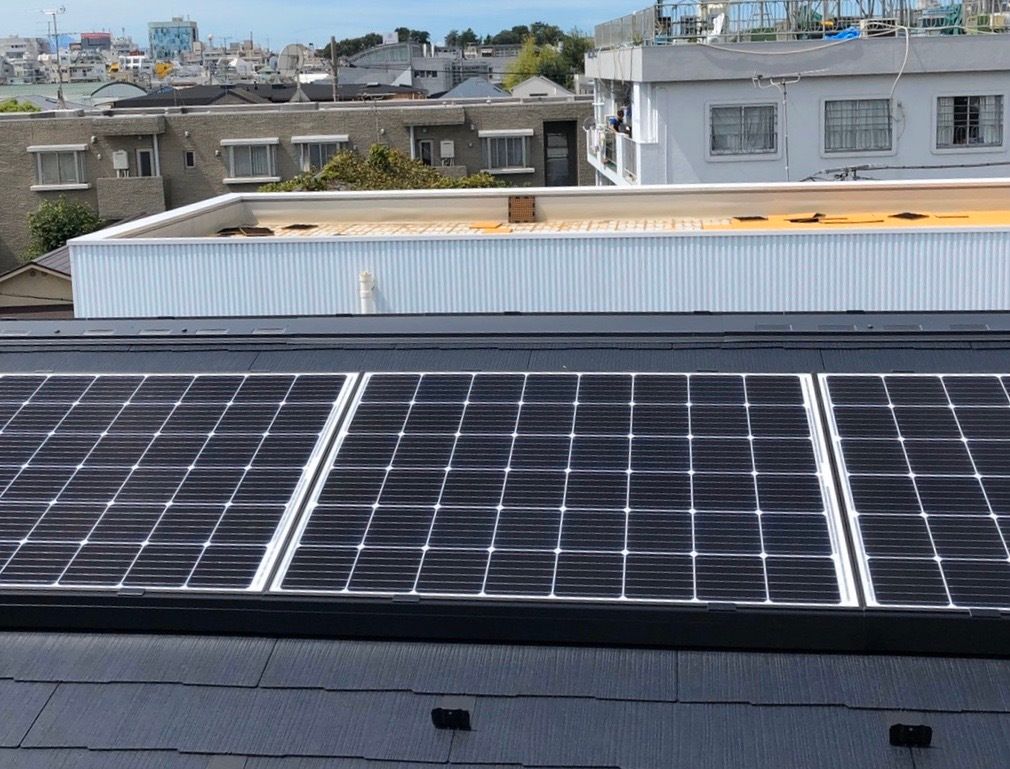 黒い屋根に並べて設置され、たくさん日の光が当たっている太陽光パネル