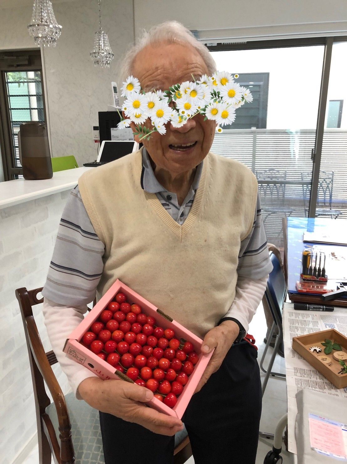 男性の入居者様が、笑顔でサクランボの入った箱を持っているお姿