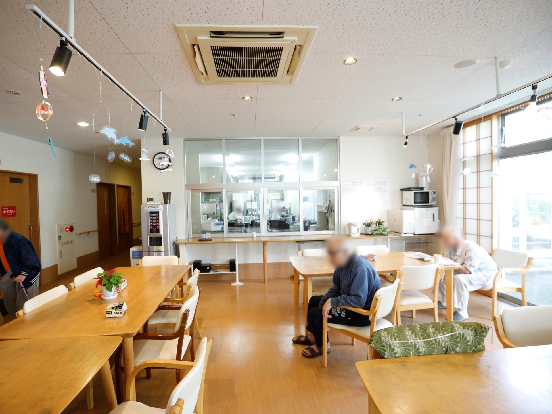 日当たりが良い共有スペースでは、入居者様がそれぞれ過ごしている。電子レンジと冷蔵庫がある。