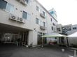 白を基調とした3階建ての建物である。2階以上にエアコンの室外機がある。ベンチを用意。