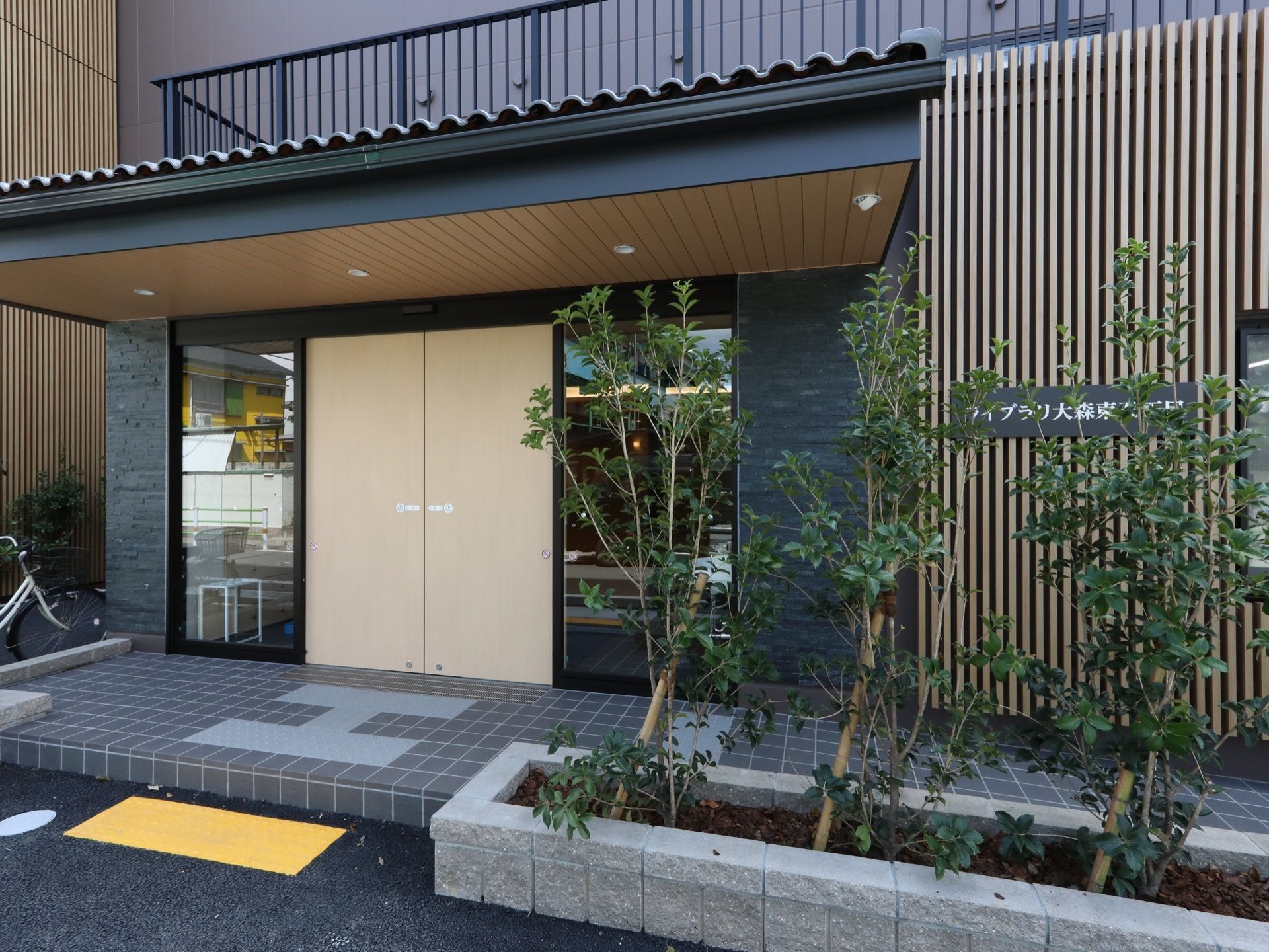玄関前の扉の前には屋根が取り付けられている。雨や強い日差しを防ぐことができるので安心である。玄関前に木々が植えられている。