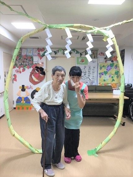 手作りの壁画がたくさん張られた共有スペースにはお手製の枠繰りがあり、マスクとエプロンを付けたスタッフと男性入居者がくぐっている。