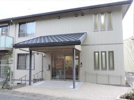 大きな屋根が付いた玄関には手すり付きのスロープと階段が付き、自動ドアが設置されている。