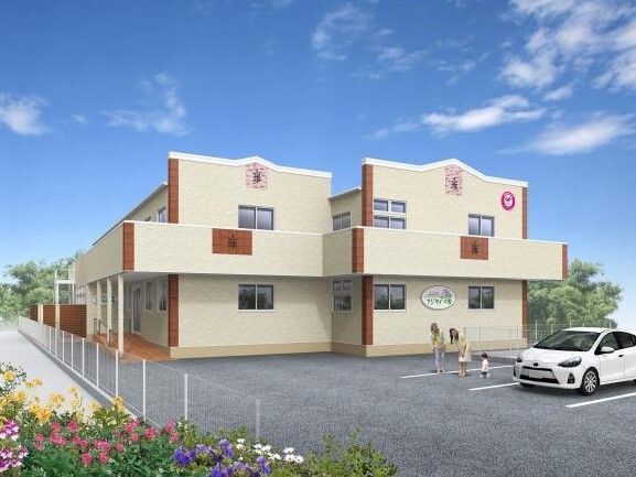 ベージュ系の2階建ての建物が日当たりのいい場所に建っている。敷地内には駐車場があり、周りには草花も植えられている。