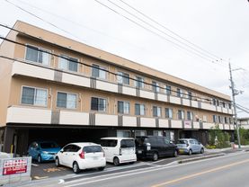 建物の1階部分の一部が、駐車場で一台停まっている。その前に2台、建物に沿って縦列で2台車がある。左側には、ブロック塀が建てられている。