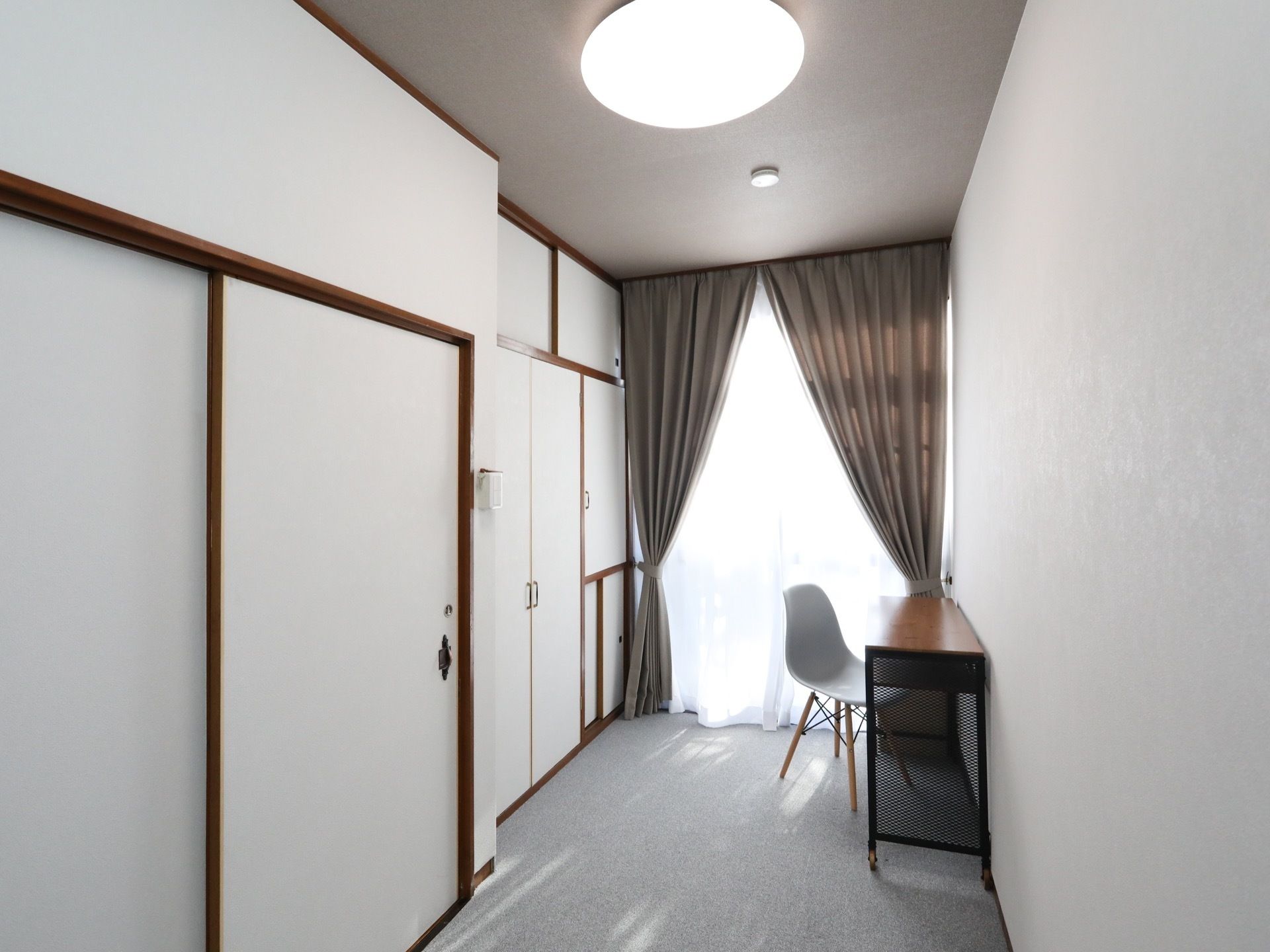白を基調とした明るい空間である。壁一面にに扉があり、複数の収納が設置されている。天井にはシーリングライトがある。