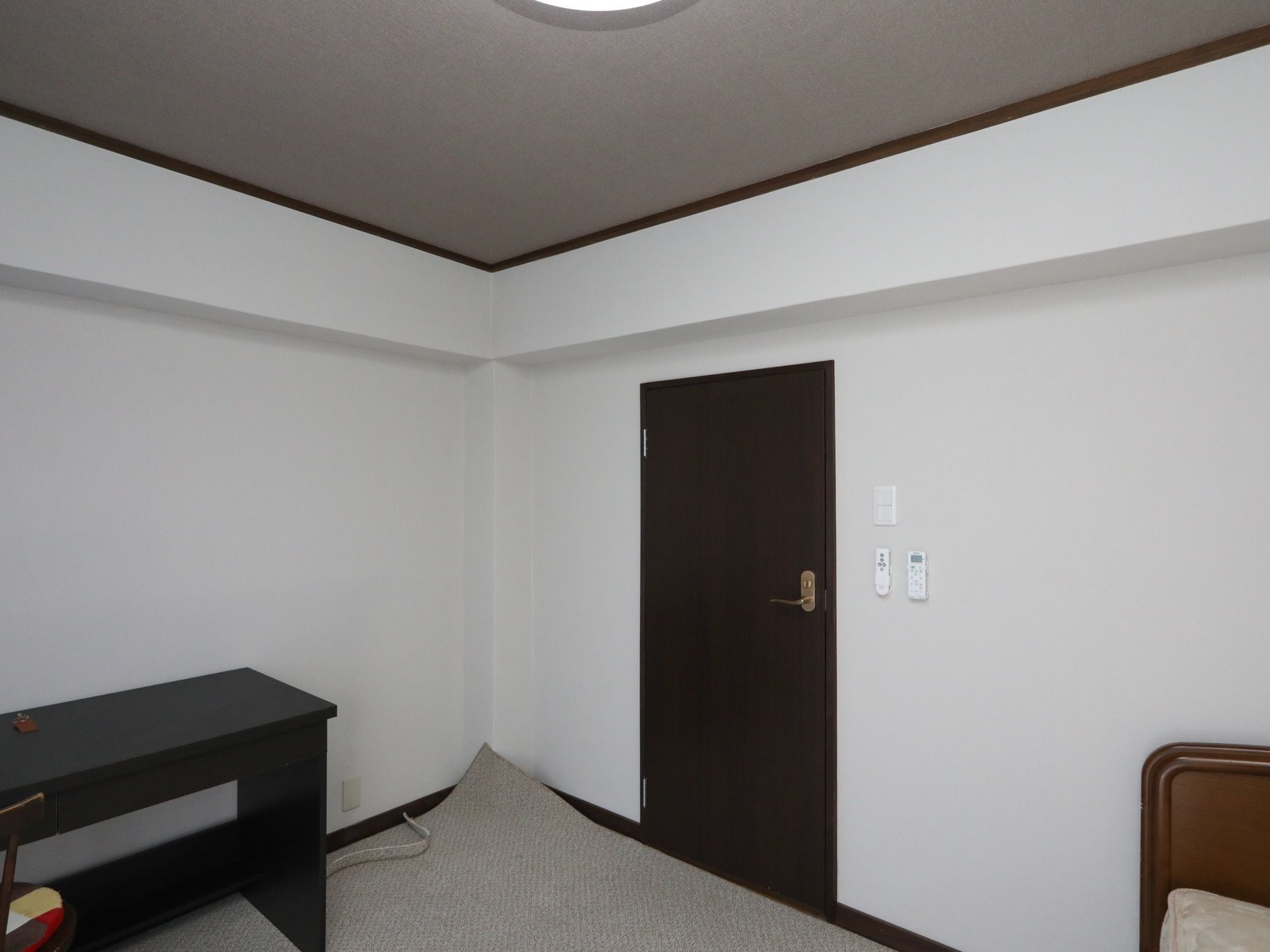 天井にシーリングライトのついた居室である。床にはグレーのカーペットが敷かれており、ベッドが１台置いてある。