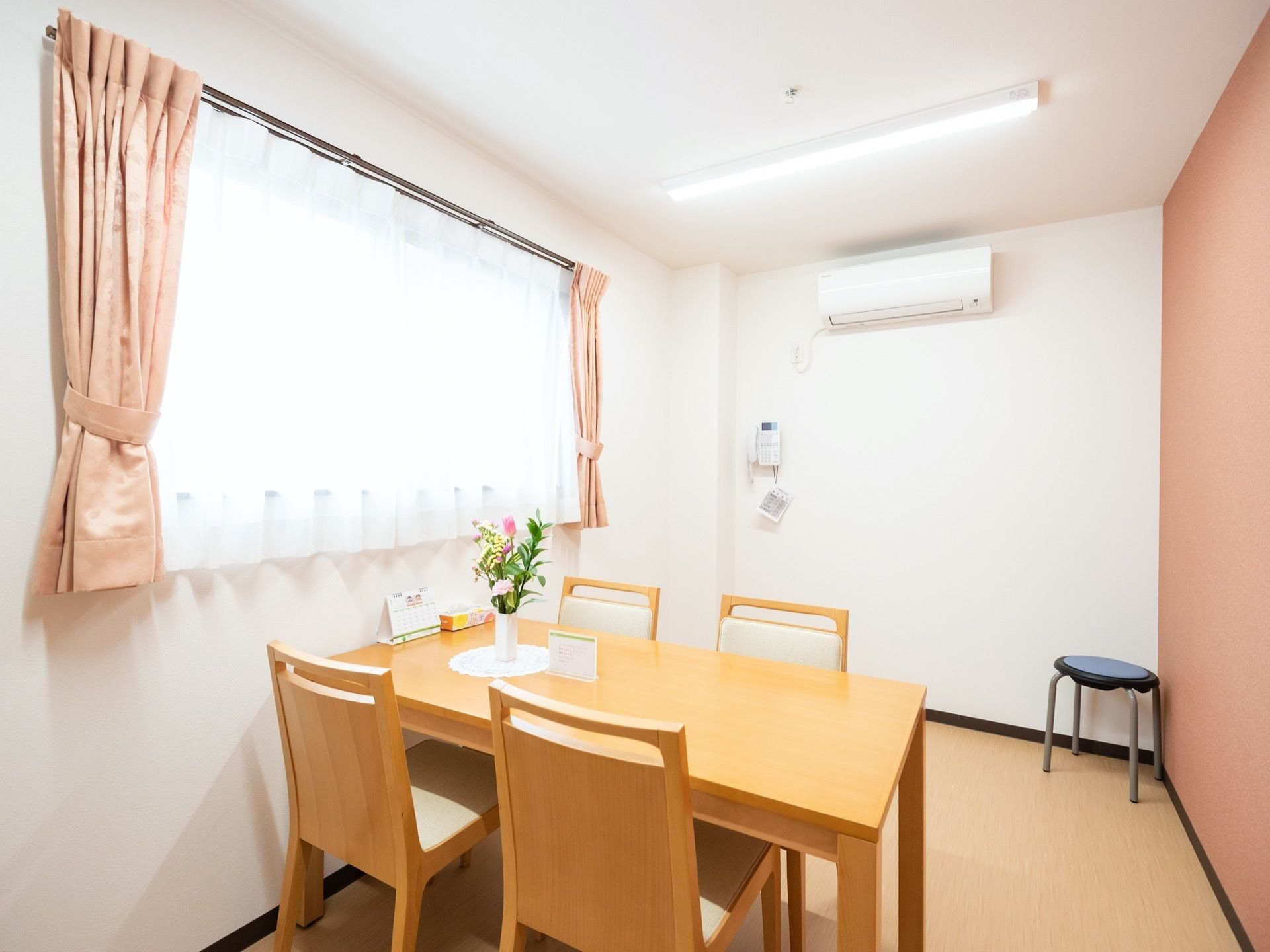 真っ白な壁で明るい相談室である。４人掛けのテーブルセットがあり、部屋の隅には丸椅子が用意されている。