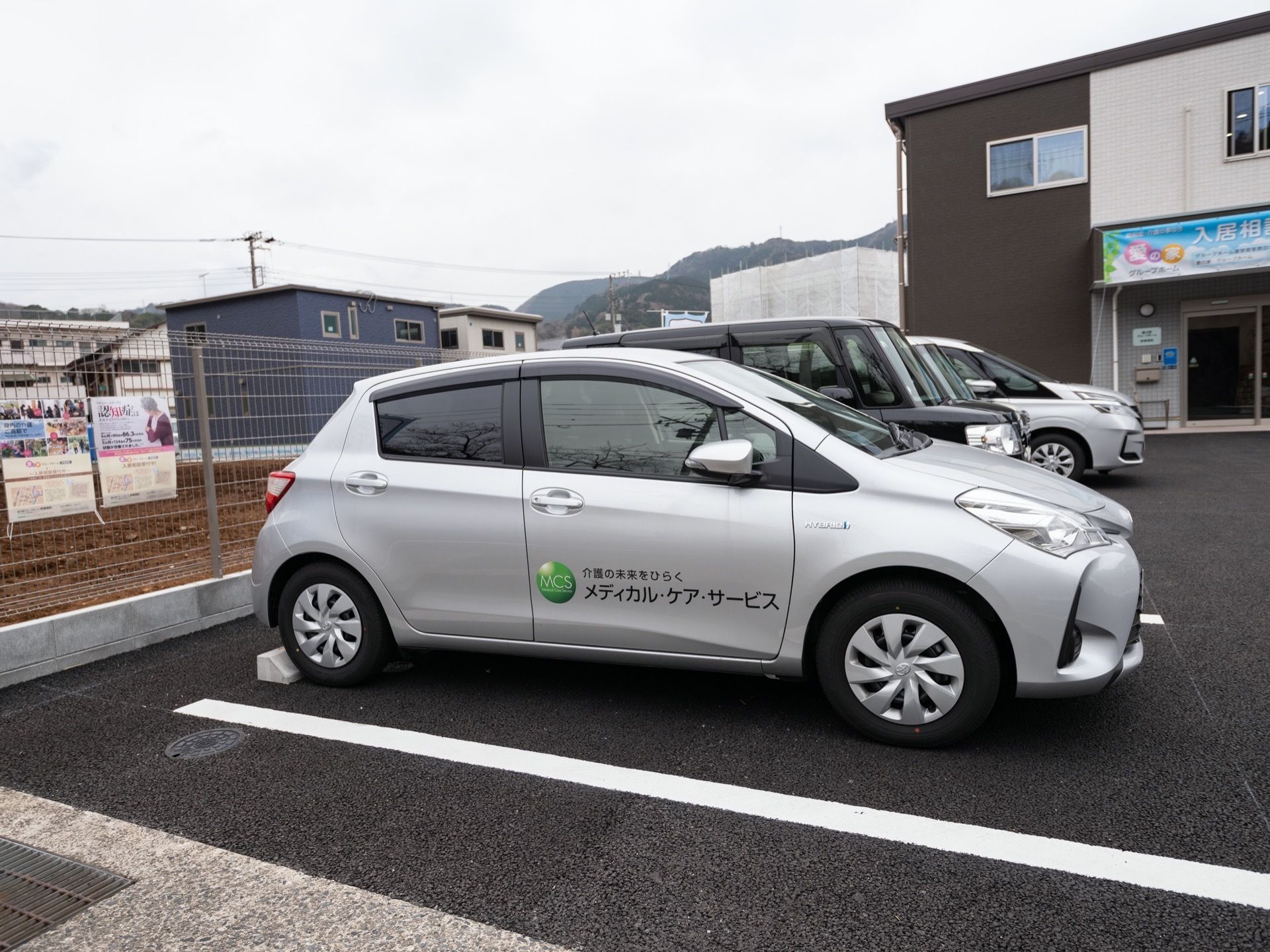 建物の横にアスファルトで整地された駐車場が完備されている。白線で仕切られている。車輪止めがあり、フェンスへの衝突を予防している。