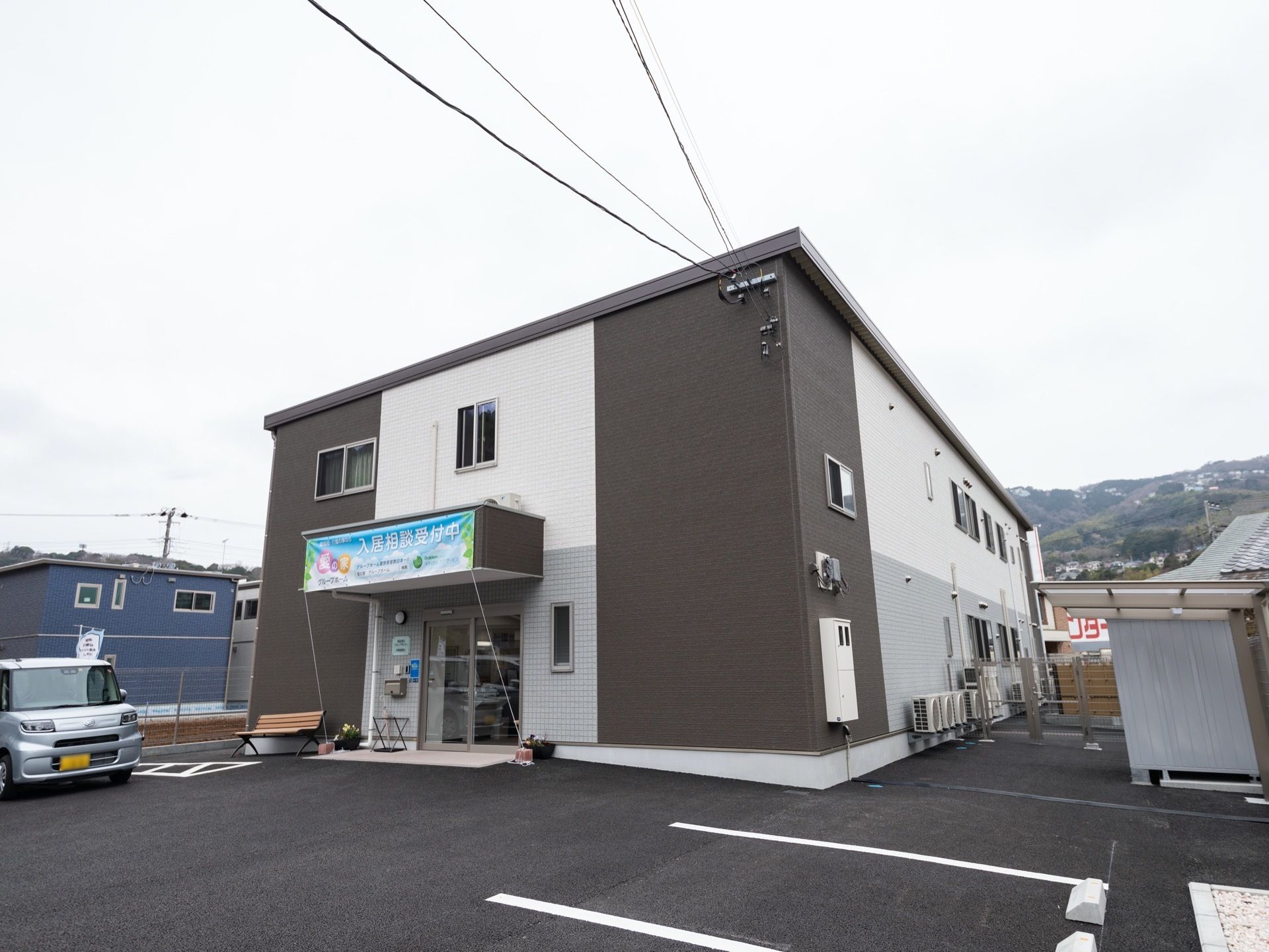 玄関前には、ベンチや季節の花が植えられたプランターが置かれている。自然に恵まれた環境のよい立地である。