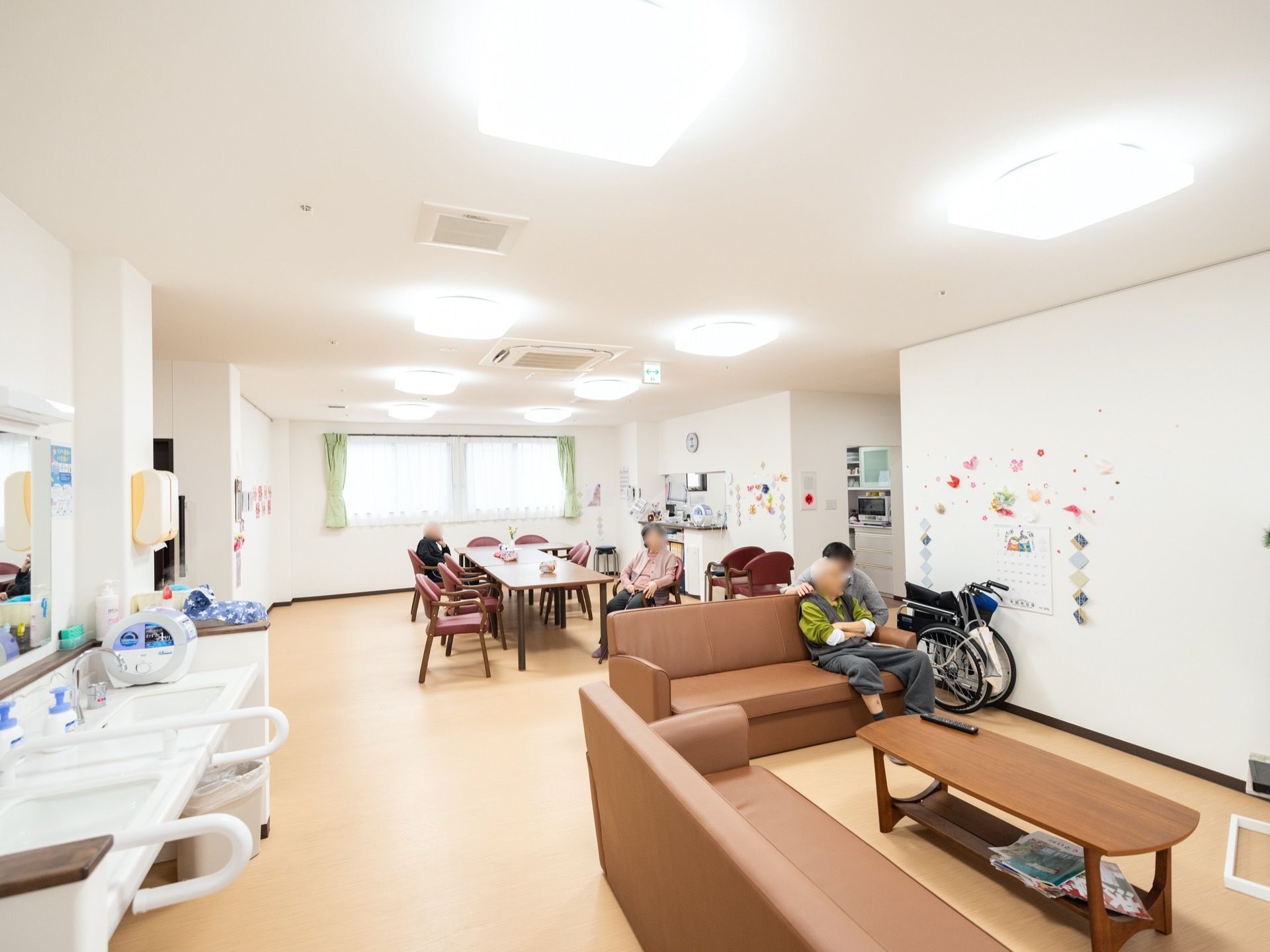 白い壁が美しい食堂である。窓からは日射しが入って明るい。リビングスペースが併設され、ソファが置かれている。