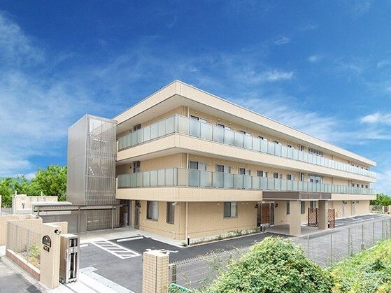 各フロアにベランダがあり、日当たりのいい場所に建っているベージュ系の外壁の３階建ての建物。