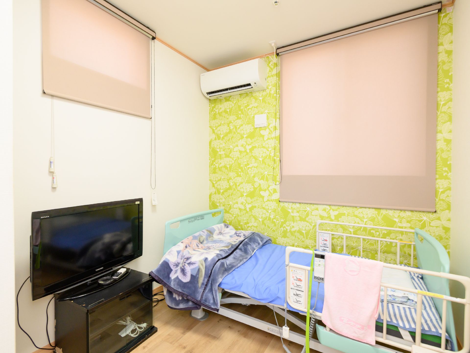 ベッドとテレビが置かれた白と緑の壁の部屋