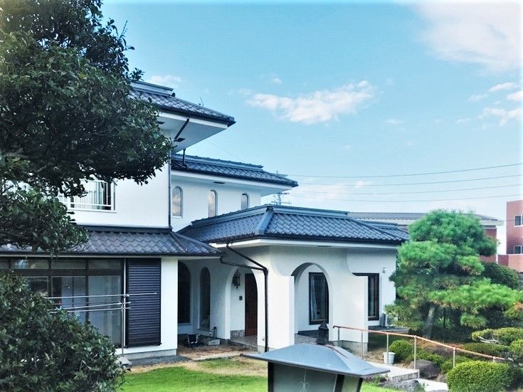 瓦屋根の2階建ての建物には庭が付き、玄関にはスロープが付いている。