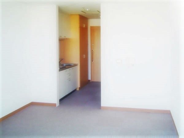 収納がたっぷりついたキッチンが付いたシンプルな居室。家具などはまだ置かれていない。