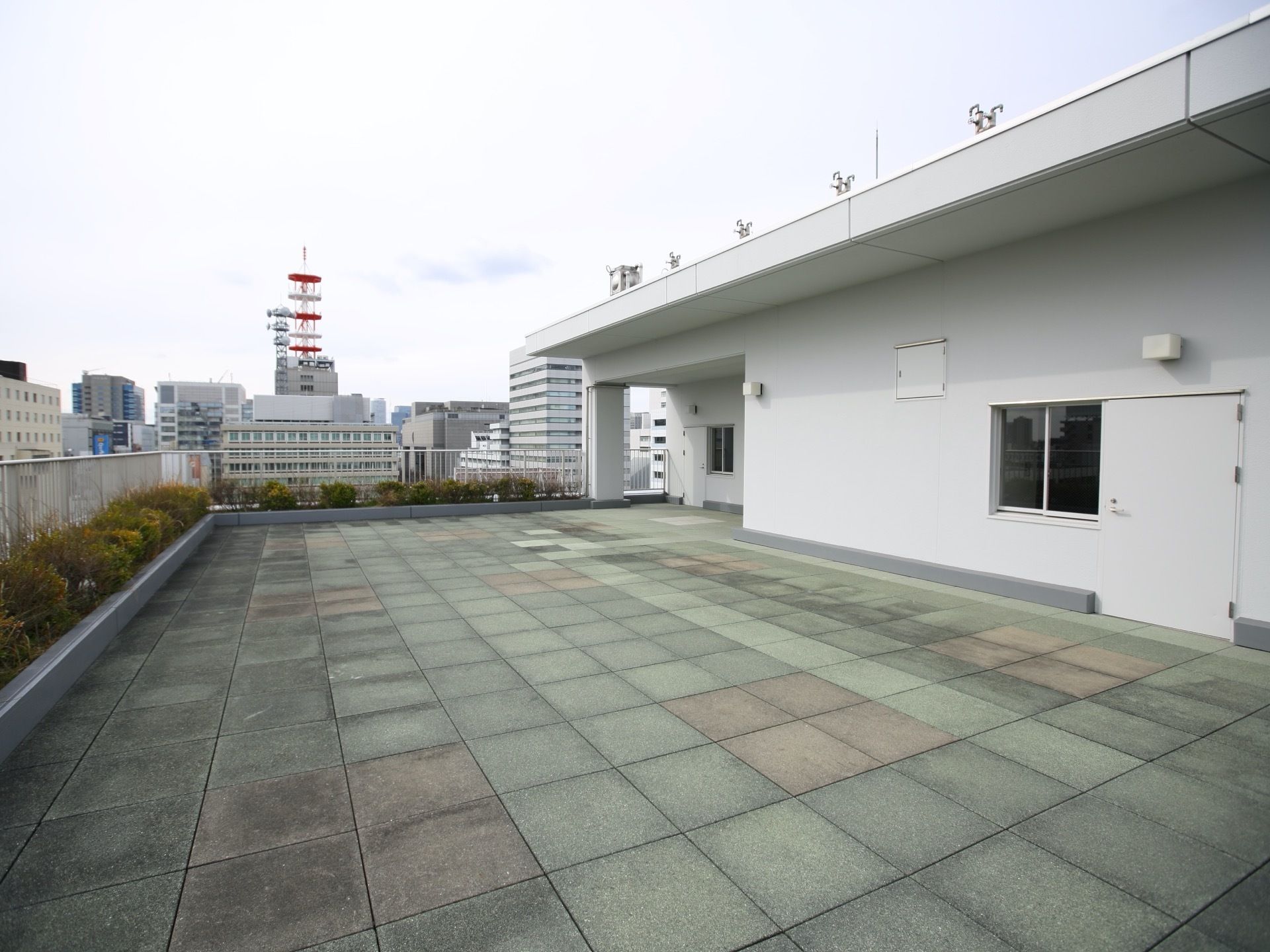 屋上にはかなり広いベランダがある。安全柵が建てられている周りには植え込みがある。周辺の街並みを見渡すことができる。