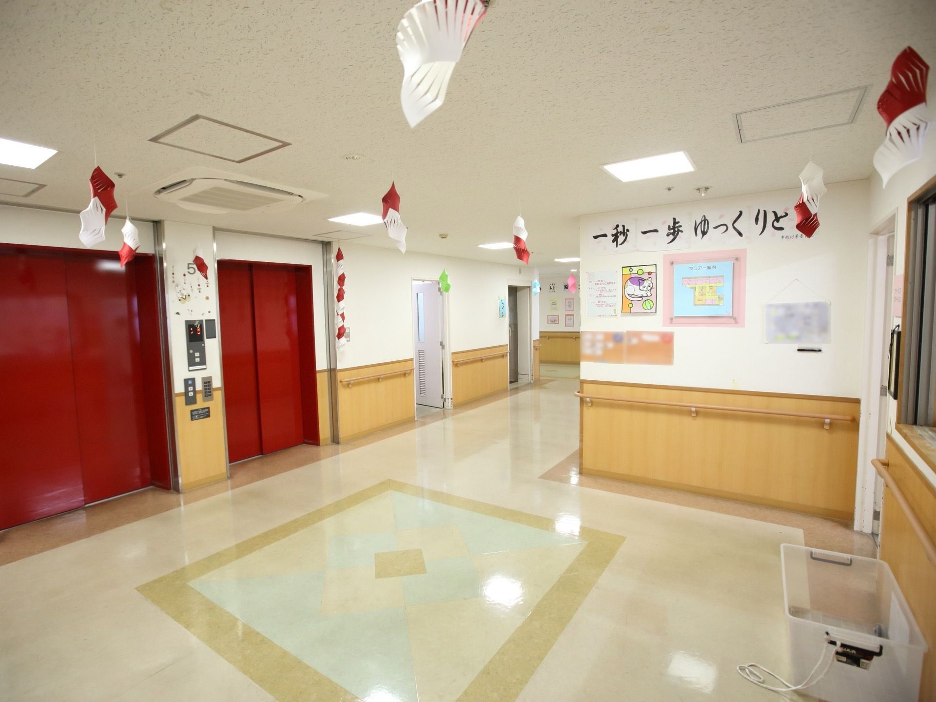 白が基調のホールには、真っ赤な扉のエレベーターが２基設置されている。目立つ色なので、入居者様は迷うことなく利用できる。