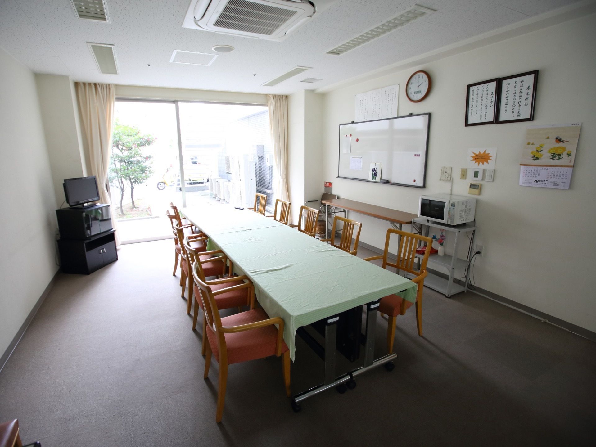 庭が見渡せる開放的な休憩スペースである。テーブルにはクロスが掛けられていて衛生的である。電子レンジやテレビが設置されている。