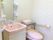 ひじ掛けが付いたトイレと独立洗面台が並ぶピンク色を基調とした洗面所