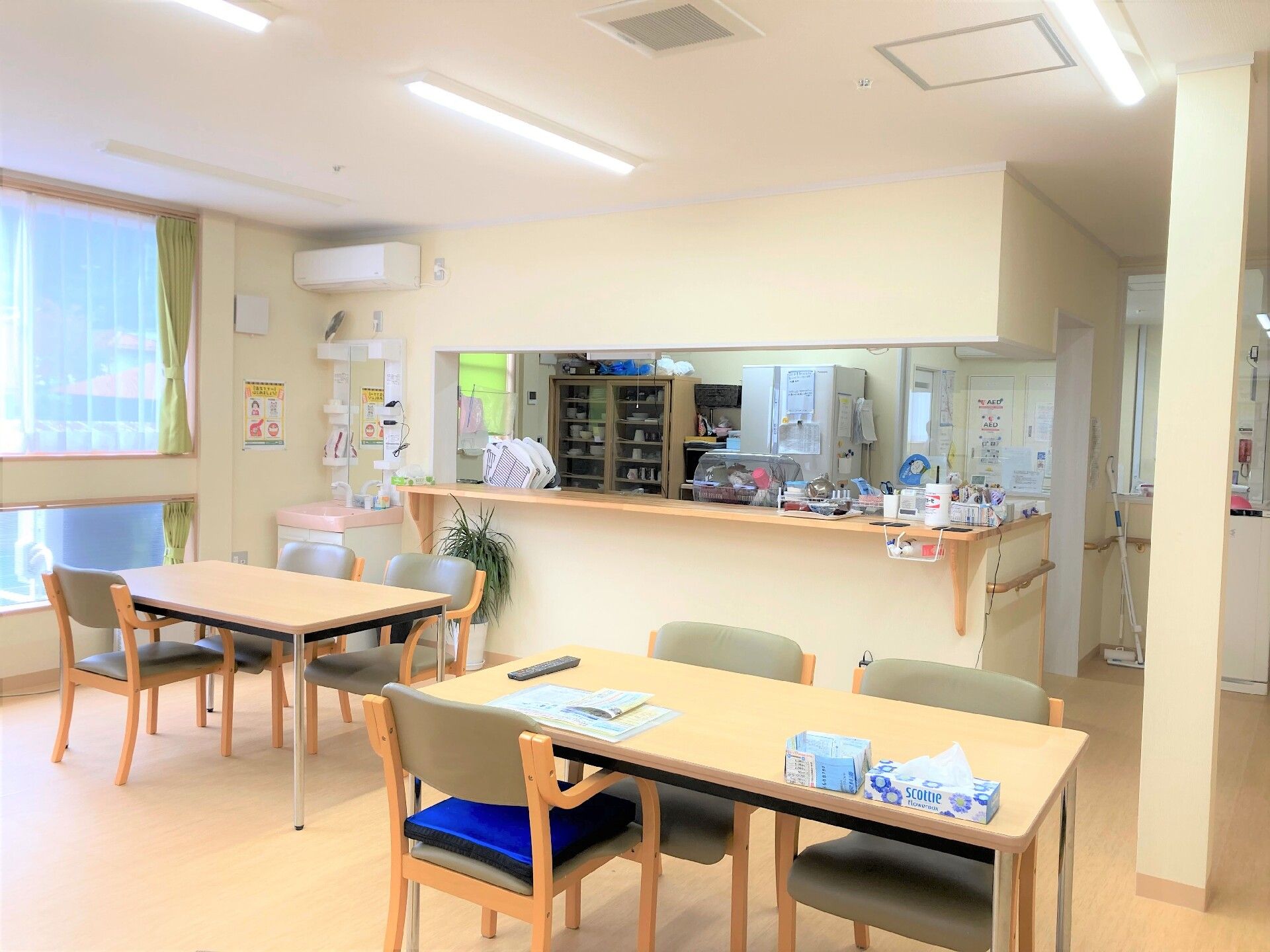 芝生の上で笑顔で話をしている高齢夫婦と女性スタッフ。男性はジャケットを着ている。