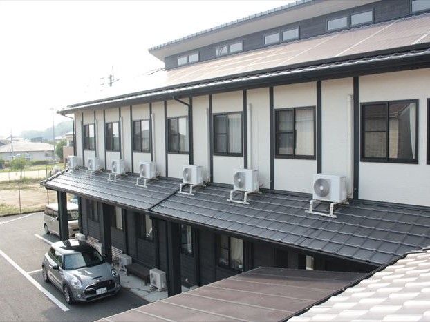 ２階建ての小さなコーポのような雰囲気の建物。手前に駐車場スペースがある様子