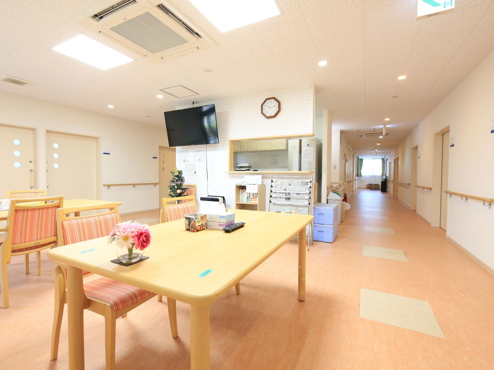 暖色で統一された温かい空間である。新聞やテレビが置かれ、入居者様が自由にそれぞれの時間を過ごすことができる。
