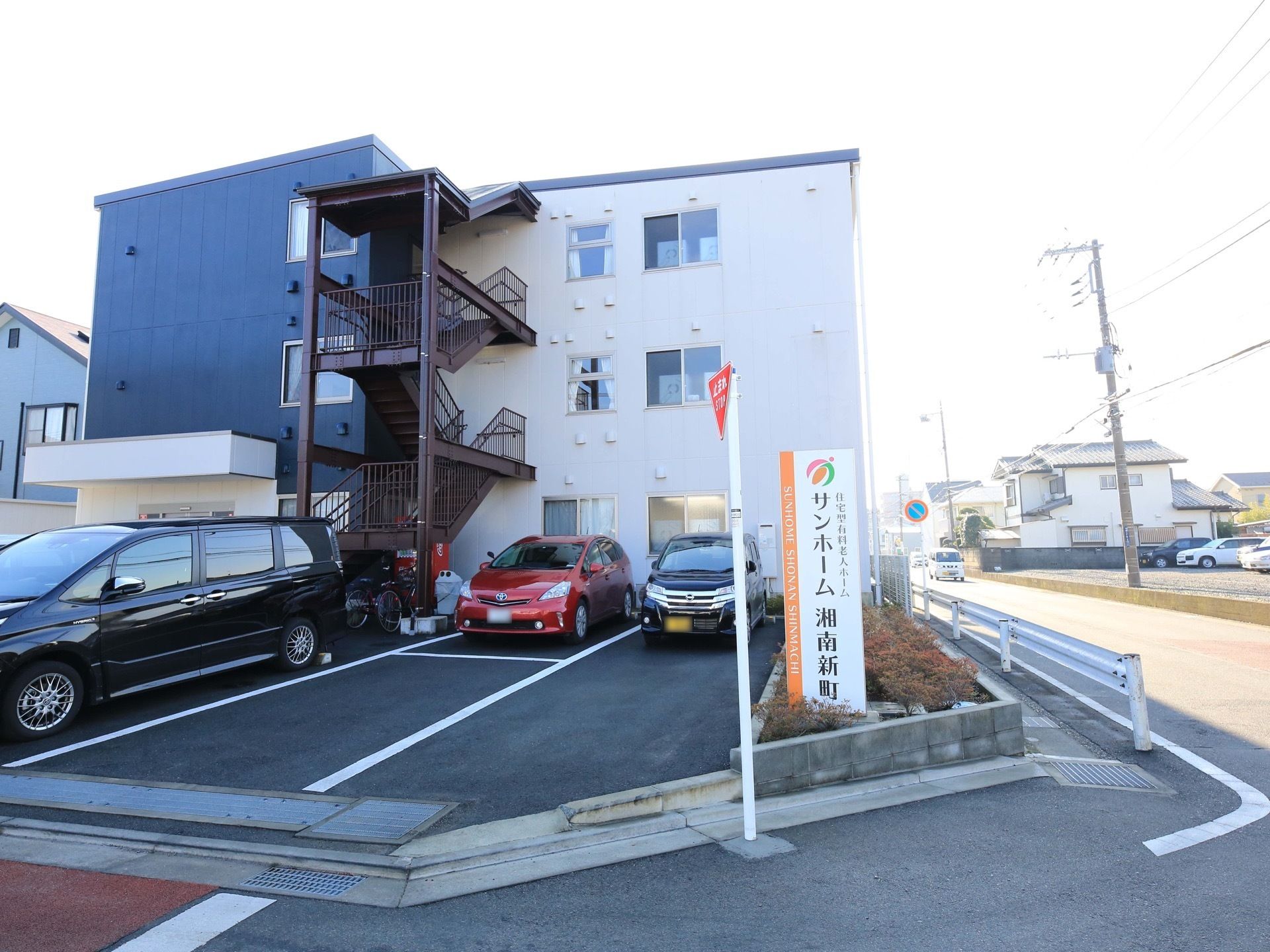 街並みに馴染む質素な建物である。道路に面した角地で、車での訪問がしやすい。複数ある窓とカーテンが開けられ、開放感がある。