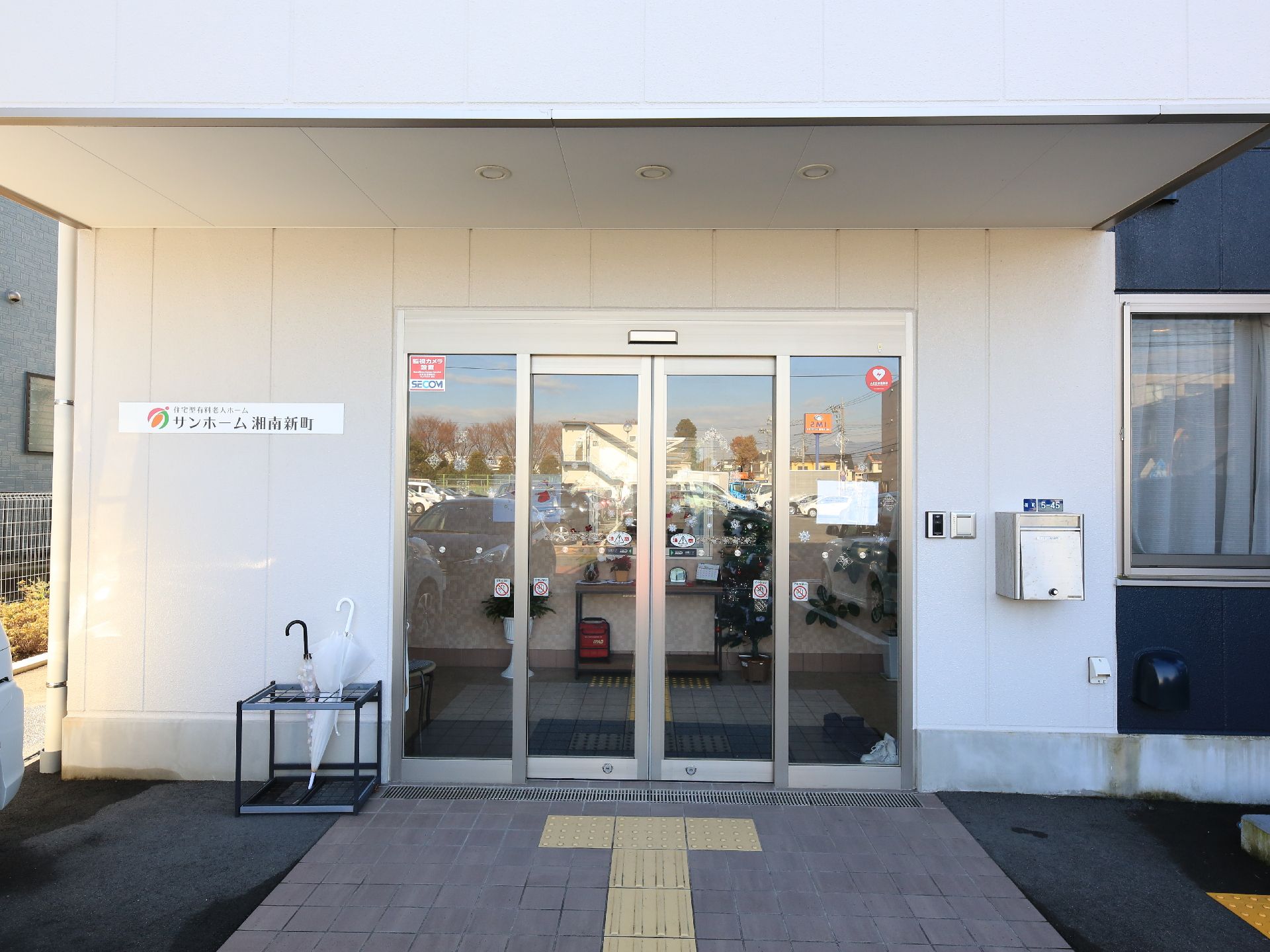 入口まで点字ブロックが敷かれ、ガラス製の自動扉が設置された玄関