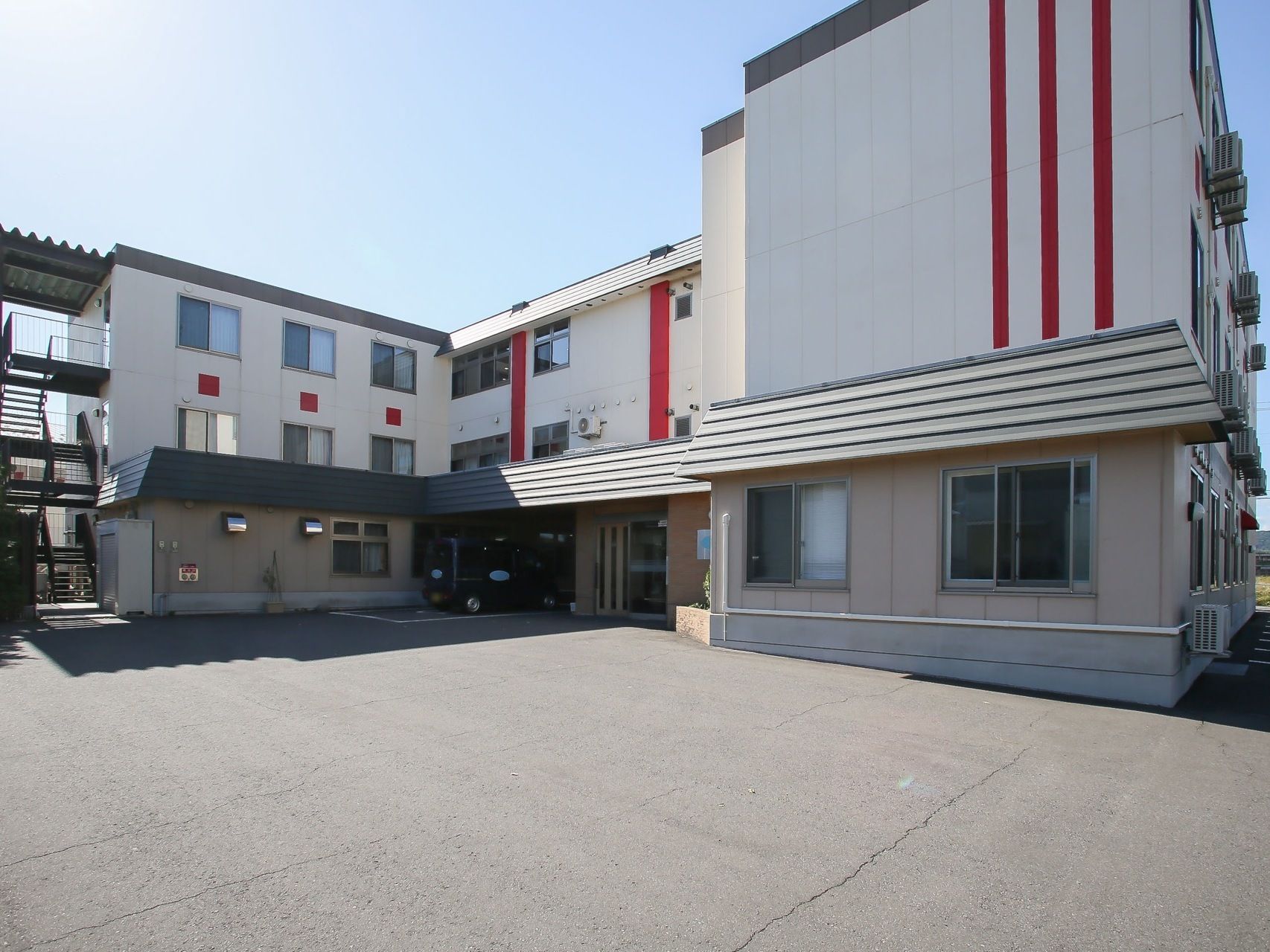 建物の外に避難階段が設置されている。施設前面の１階部分には小屋根がついており、玄関部は車を停めたときに雨に濡れないようになっている。