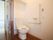 開き戸タイプの扉を開けるとトイレがある。暖房洗浄便座で、その脇の壁には、ひも付きのナースコールや手すりが設置されている。