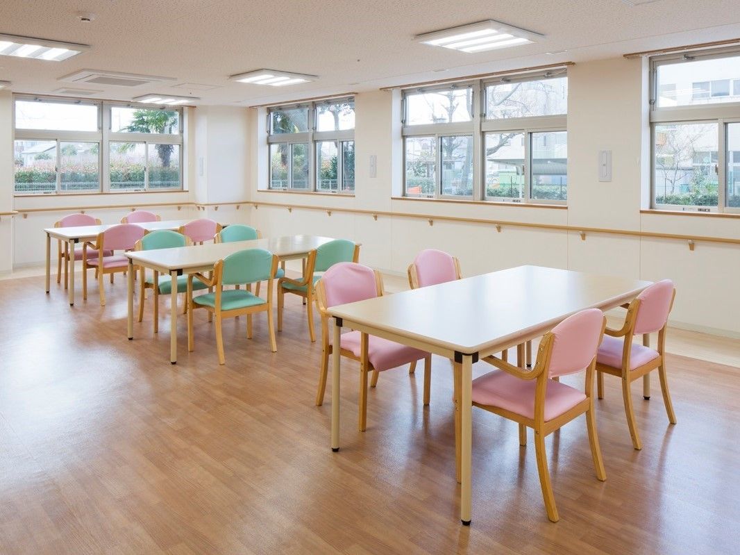 窓がたくさんついた食堂にはピンクやグリーンの椅子がセットされたテーブルセットが置かれている。