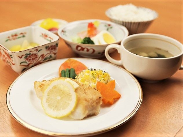 金色のふちがついたお皿に、魚のムニエルが載っている。